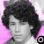 Black-and-white portrait of a person with curly hair against a pink background, with text overlays in black rectangles.