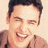 A pixelated image of a person with short dark hair wearing a brown shirt, next to green text on a dark background.