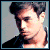 Pixelated portrait of a person with dark hair styled in two rounded buns, wearing a black top against a light gray background.