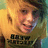 Pixelated close-up of a person with light brown hair and fair skin wearing a yellow shirt, with dark text on the chest.