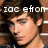 A pixelated image of a person with brown hair against a brick wall background, featuring overlaid text in white block letters.