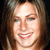 A pixelated close-up of a smiling person with light brown hair against a dark background, showing visible teeth and a bright facial expression.