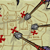 Static pixelated map icon with beige background, brown lines forming paths, gray circular nodes connected by red X-shaped markers on a grid-like layout.