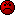 Red pixelated face with black square eyes, a horizontal mouth line, and scattered black pixels on its surface against a gray background.