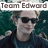 Pixelated image of a person with light brown hair wearing dark sunglasses and a dark blue shirt against a green background with text overlays.
