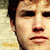 Static close-up of a person's face with dark hair and light skin, rendered in low-resolution pixelated style on a pale background.