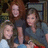 Three pixelated figures with brown hair, wearing dark tops and blue bottoms, positioned closely together in a group pose.