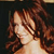 Pixelated close-up of a person with brown hair against a dark background, showing shoulder and neck area.