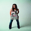A woman with long brown hair stands in a light blue background wearing a floral tank top and blue jeans, with a close-up view of her face on the right.