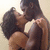 Two people in a close embrace, lips touching in a kiss, with one person's arm around the other's back.