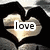 A heart-shaped icon with a gradient fill of beige and brown tones, featuring the word 'love' in white pixelated text centered on its surface.