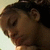 Pixelated close-up of a person's face with dark hair, closed eyes, and light skin tone against a pale background.