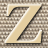 Static pixelated icon of a stylized letter Z on a beige background with dark brown border, set against a checkered patterned backdrop.