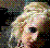 Pixelated close-up of a person's face with light skin tones, dark eyes, and brown hair against a black background with scattered colored pixels.