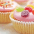 Pixelated image of a cupcake with pink frosting, green and red toppings on a white plate.