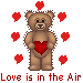 Pixelated brown teddy bear holding red heart, surrounded by floating hearts on gray background with text "Love is in the Air" below.