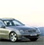 Pixelated static image of a light blue sedan car on a road with a pale sky background.