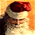 Santa Claus figure with red hat and white beard on warm-toned background, next to green with pixelated text