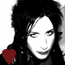 Black-and-white pixelated image of a person with long dark hair, closed eyes, and a red heart symbol in the bottom-left corner.