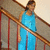 Pixelated figure in blue dress stands against striped background with diagonal brown lines.