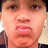 Pixelated close-up of a person's face showing eyes, nose, mouth with lips parted and teeth visible, wearing dark clothing against light background.