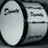 A grayscale drum with visible text on its surface, accompanied by pixelated text reading 'all about the bass baby!' on a black background.