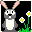 Pixelated bunny with gray body and white belly stands against black background, surrounded by green grass and white daisies with yellow centers.