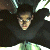 Pixelated figure in dark clothing with arms raised, light-colored face, and green-tinted lower body against dark background.