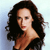Pixelated image of a person with long dark hair wearing a black top, set against a light blue gradient background.