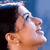 Pixelated close-up of a person's face in profile with visible ear, nose, and mouth against blue background.