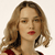 Pixelated close-up of a person with light brown wavy hair, red lips, and a red and black garment against a light background.
