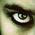 Pixelated close-up of a stylized eye with a spiral pupil, dark eyelashes, and a light greenish-yellow background.