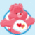 Pink Care Bear with heart emblem on chest, blue circular border, light blue background with white dots, pink text reading Let me hug you.