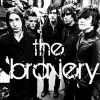 Black-and-white image of five people standing together with overlaid text reading 'the brony' in stylized font.