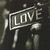 A static image with a dark, grainy background featuring repeated white 'LOVE' signs and red/blue text overlays.