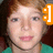 Pixelated close-up of a person with light skin, brown hair, and pink lips wearing a green top; orange icon overlay on right side.