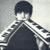 Pixelated grayscale image of a person with short dark hair wearing a checkered jacket over a dark shirt against a light gray background.