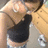 A pixelated close-up of a person's upper body wearing a dark sleeveless top and light-colored shorts, with a black strap visible across the chest.