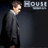 A man in a dark suit and white shirt stands against a black background with 'HOU' text visible, his head turning from left to right across frames.