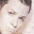 Pixelated close-up of a person's face with light skin tone, dark hair, and visible eyes and nose against a light background.