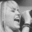 Black-and-white pixelated image of a person with light hair holding a microphone, next to bright pink background with blue text.