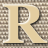 Static 48x48 pixel icon featuring a large beige letter R with dark brown and black accents on a checkered background.