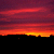 A static pixelated image of a sunset with horizontal bands of red, orange, and yellow transitioning into dark purple at the top.