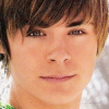 A close-up portrait of a person with light brown hair and fair skin, wearing a green and white patterned garment.