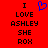 Red background with black pixelated text reading "I LOVE ASHLEY SHE ROX" and a blue heart symbol above the word LOVE.