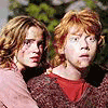 Four characters in school uniforms stand side-by-side, two with red hair and two with brown hair, against a blurred green background.