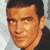Pixelated static image of a man's face with dark hair and light skin tone, cropped to show upper head and shoulders against a gray background.
