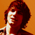 Pixelated static image of a person with dark hair against an orange background, showing partial facial features and shoulder area in low-resolution 256x256 format.