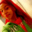 Pixelated image of a character with long red hair, orange skin tone, and green lower body against light background.