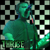 A person singing into a microphone with a checkered background and 'THRICE' text at the bottom.